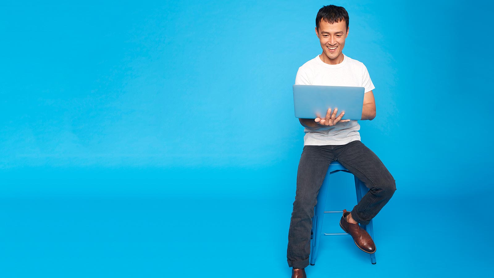 Man sitting on a chair using a laptop.